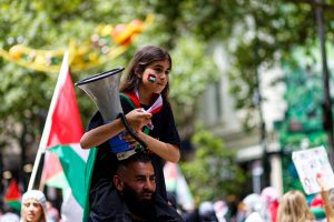 Child sits on her fathers should leading chants in support of Palestine.