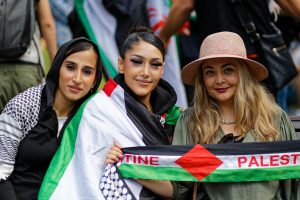 Three women rest after the march arrives back at the State Library, Melbourne.