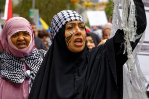Woman holding the giant keffiyeh at a ceasefire now rally in Melbourne.
