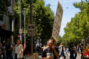 Man with a banner saying AUKUS complicit in genocide.