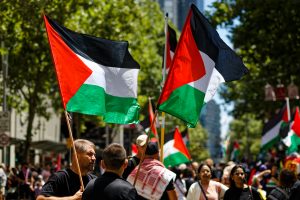 People with Palestinian flags at the Gaza ceasefire rally in Melbourne.