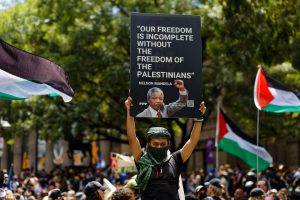 Person holding a sign with a Nelson Mandela quote: Our freedom is incomplete without the freedom of the Palestinians.